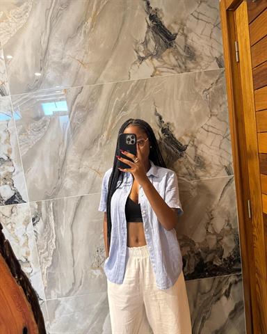 A Claudia a tirar uma selfie ao espelho, com o telemóvel à frente da cara, junto a uma parede de mármore