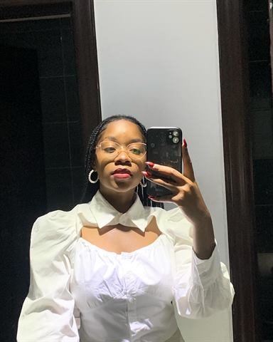 Selfie da Claudia ao espelho, de óculos, batom vinho e blusa branca de mangas bufantes